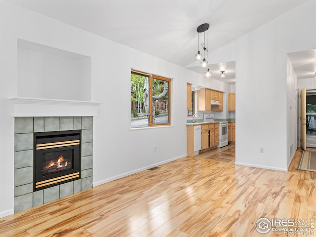 1010 S Saint Vrain Ave S, Estes Park, CO 80517 - unfurnished living room with a fireplace, light wood-type flooring, lofted ceiling, a sink, and baseboards