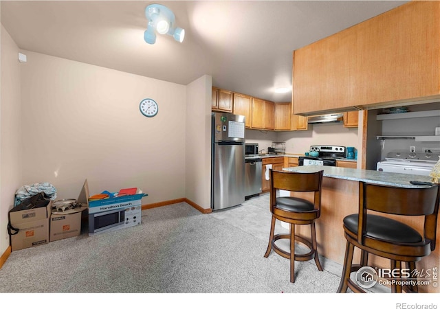 1640 Kirkwood Dr Unit 2011, Fort Collins, CO 80526 - kitchen with light carpet, a kitchen breakfast bar, appliances with stainless steel finishes, a peninsula, and under cabinet range hood