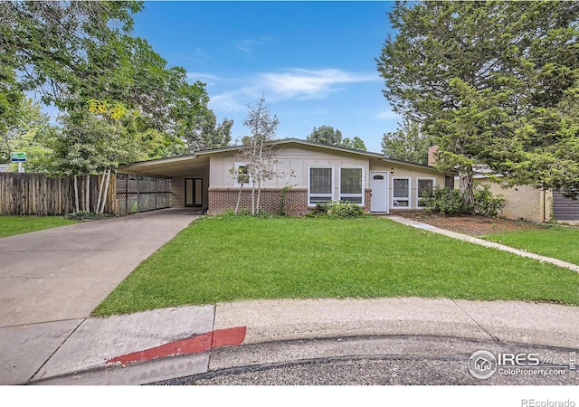 view of front of house featuring fence, a front yard, brick siding, driveway, and a carport
