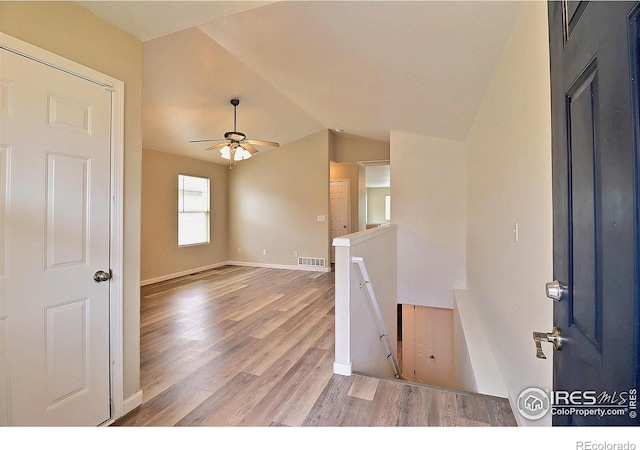 foyer entrance featuring visible vents, baseboards, ceiling fan, light wood-type flooring, and lofted ceiling