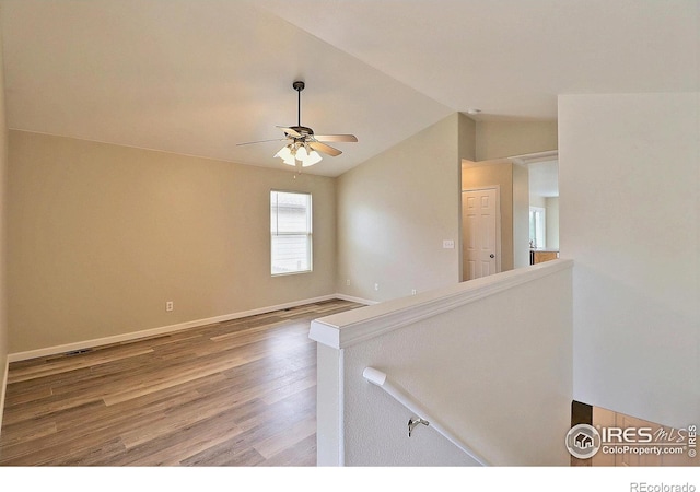 spare room with wood finished floors, ceiling fan, baseboards, and vaulted ceiling