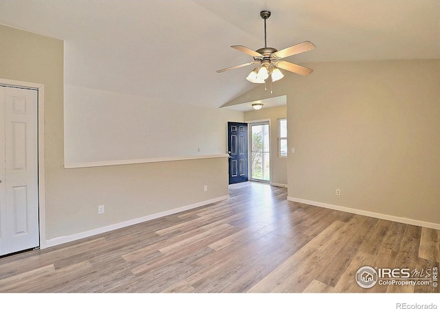 empty room with vaulted ceiling, light wood-type flooring, baseboards, and ceiling fan