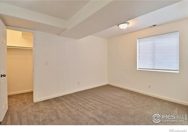 unfurnished bedroom featuring carpet, a closet, visible vents, a walk in closet, and baseboards