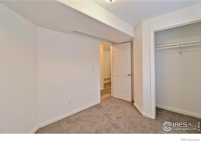 unfurnished bedroom with a closet, carpet flooring, and baseboards