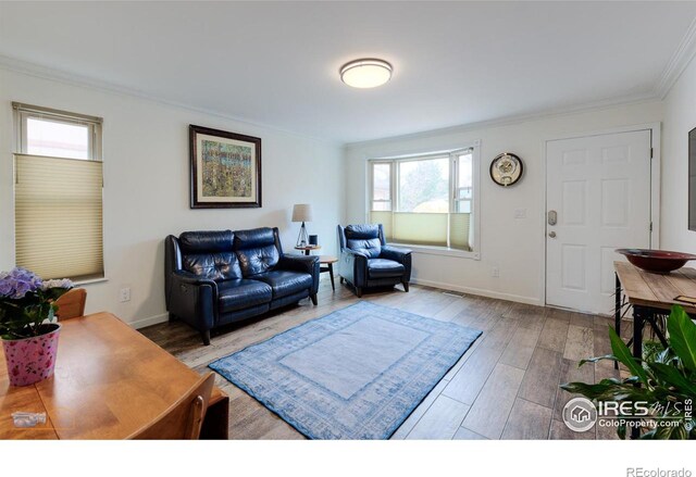living room featuring baseboards, crown molding, and wood finished floors