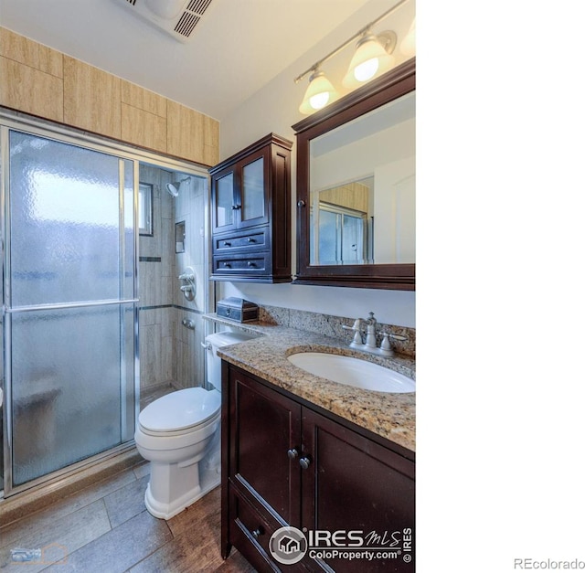 bathroom featuring vanity, visible vents, toilet, and a shower stall