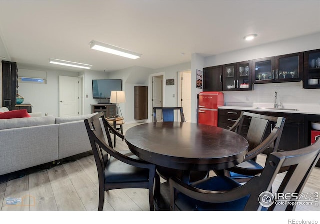 dining space featuring light wood-type flooring and indoor bar