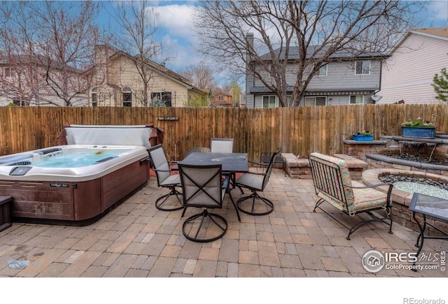 view of patio / terrace with a fenced backyard, outdoor dining space, and a hot tub