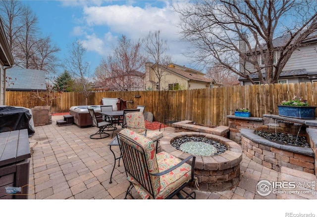 view of patio with a fenced backyard, a fire pit, area for grilling, and a hot tub