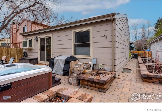 back of property featuring an outdoor fire pit, fence, a hot tub, and a patio area
