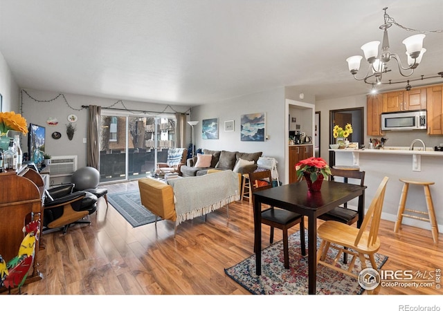 1315 Kirkwood Dr Unit 804, Fort Collins, CO 80525 - dining area featuring a wall unit AC, a notable chandelier, and light wood finished floors