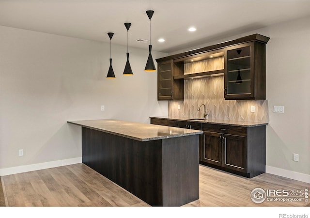 5977 Crooked Stick Dr, Windsor, CO 80550 - indoor wet bar featuring light wood-style flooring, tasteful backsplash, decorative light fixtures, and recessed lighting