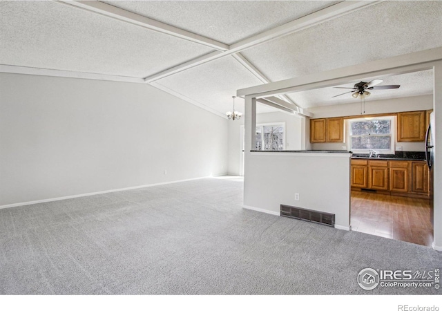 kitchen with vaulted ceiling with beams, brown cabinets, light colored carpet, and visible vents