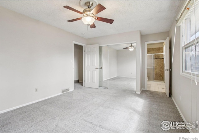 empty room with a ceiling fan, carpet floors, a textured ceiling, and visible vents
