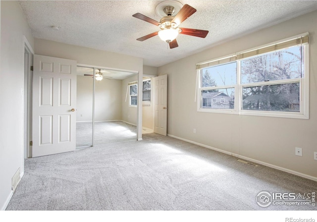 unfurnished bedroom with a ceiling fan, a textured ceiling, baseboards, visible vents, and carpet