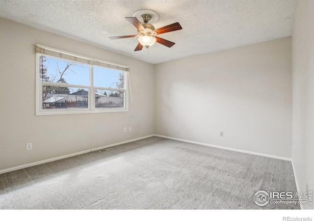 empty room featuring carpet floors, a ceiling fan, a textured ceiling, baseboards, and visible vents