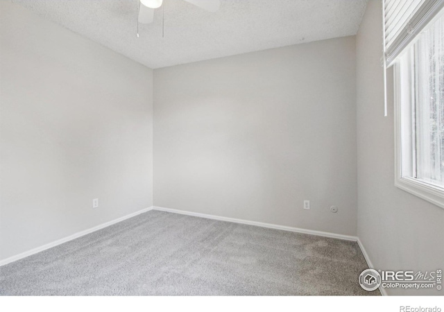 carpeted spare room with baseboards, ceiling fan, and a textured ceiling