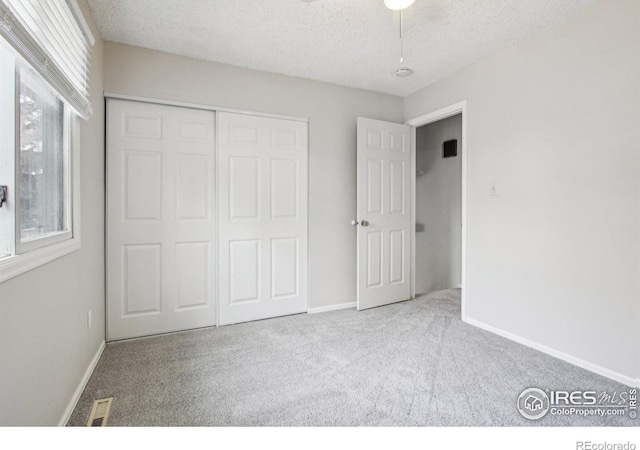 unfurnished bedroom with baseboards, a textured ceiling, carpet floors, visible vents, and a closet