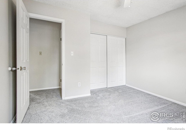 unfurnished bedroom featuring a closet, carpet flooring, a textured ceiling, and baseboards