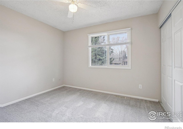 unfurnished bedroom with carpet flooring, baseboards, a textured ceiling, a ceiling fan, and a closet