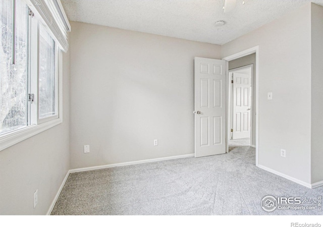 carpeted empty room featuring baseboards and a textured ceiling