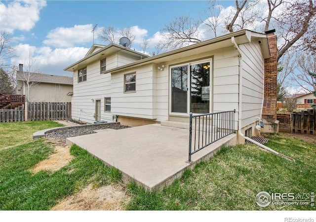 rear view of property with fence, entry steps, a patio, a chimney, and a lawn