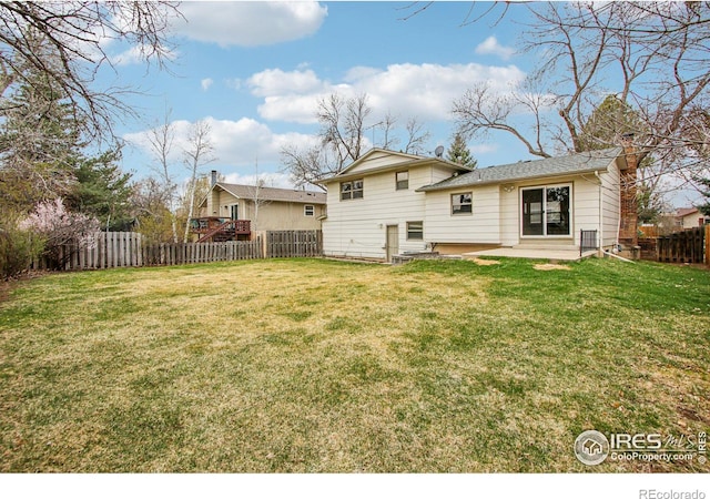 rear view of property with a fenced backyard, a yard, and a patio area