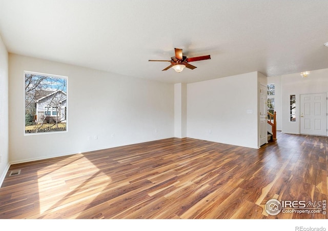 unfurnished room featuring stairs, wood finished floors, ceiling fan, and visible vents