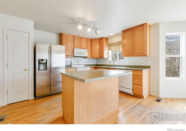 kitchen with backsplash, light wood finished floors, a center island, white appliances, and visible vents