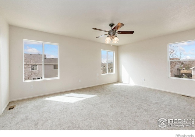 carpeted empty room featuring baseboards, visible vents, and a ceiling fan
