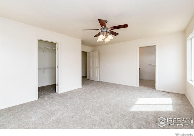 unfurnished bedroom with a spacious closet, carpet flooring, a closet, and ceiling fan