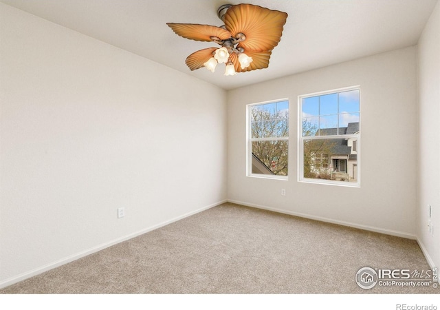 carpeted spare room featuring baseboards and ceiling fan