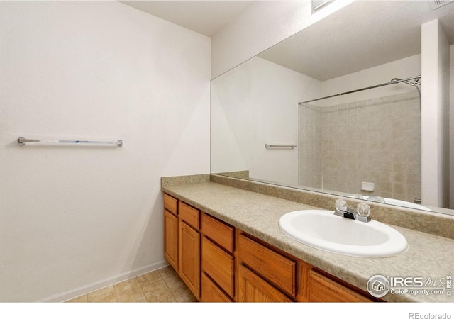 full bathroom with baseboards, visible vents, walk in shower, and vanity