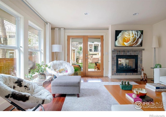living area featuring french doors, recessed lighting, a tiled fireplace, and wood finished floors