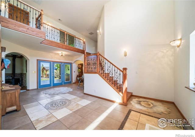4514 Hoot Owl Dr, Berthoud, CO 80513 - tiled entrance foyer featuring arched walkways, french doors, a towering ceiling, stairway, and baseboards
