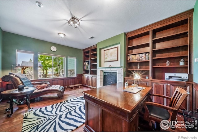 4514 Hoot Owl Dr, Berthoud, CO 80513 - office featuring wood finished floors, a fireplace, a textured ceiling, and built in features