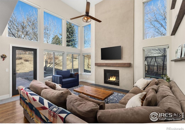 501 W Linden St, Louisville, CO 80027 - living room featuring a fireplace with flush hearth, baseboards, a towering ceiling, wood finished floors, and a ceiling fan