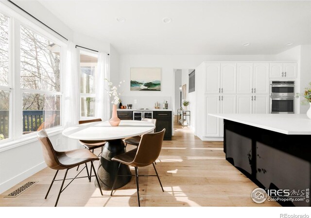 dining space with baseboards, visible vents, and light wood-style flooring