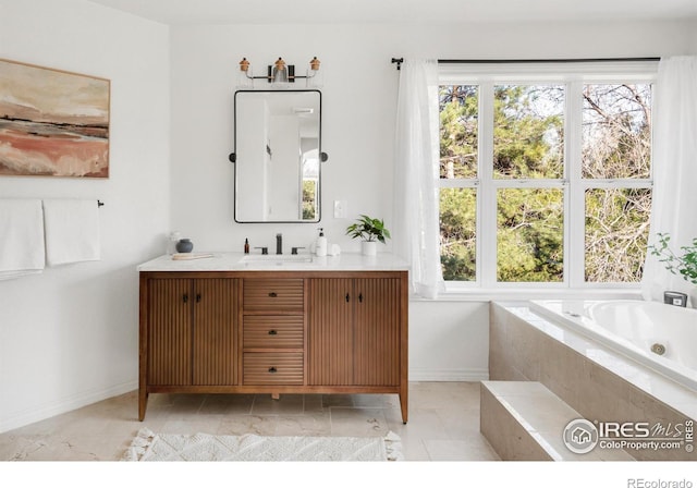 bathroom featuring a wealth of natural light, a tub with jets, vanity, and baseboards
