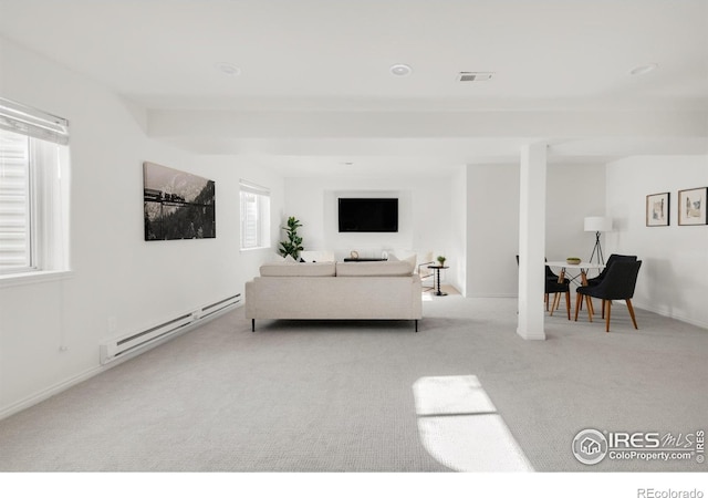 living room with a baseboard heating unit, baseboards, visible vents, and light colored carpet