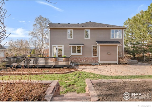 rear view of house with a wooden deck, brick siding, and a patio