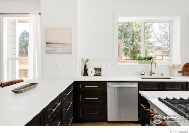 interior space featuring stainless steel dishwasher, a sink, and light countertops
