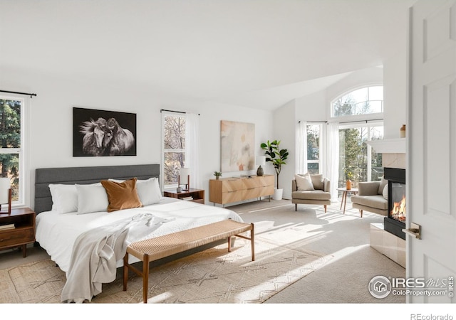 carpeted bedroom with vaulted ceiling, access to exterior, and a fireplace