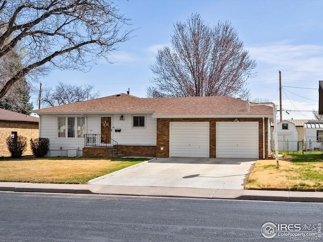 ranch-style house featuring a front yard, concrete driveway, fence, a shingled roof, and a garage