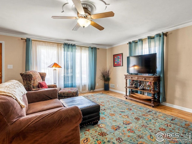 living area with baseboards, ceiling fan, wood finished floors, and crown molding