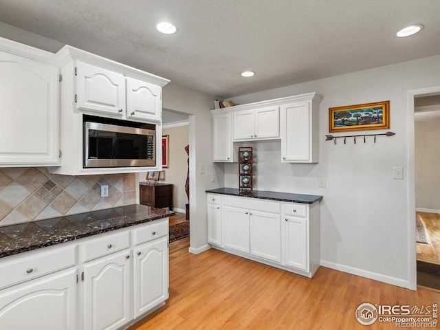 kitchen with stainless steel microwave, light wood-style flooring, and white cabinetry