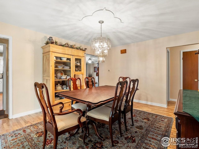 dining area with baseboards, light wood-style flooring, and a chandelier