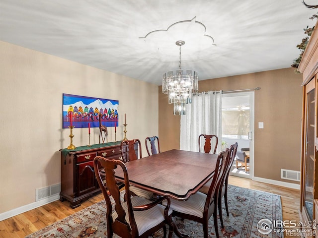 dining space featuring visible vents, light wood-style flooring, and an inviting chandelier
