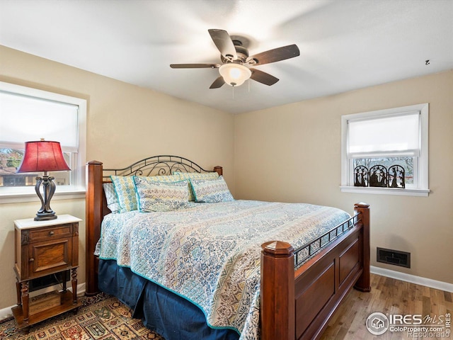 bedroom featuring baseboards, visible vents, wood finished floors, and a ceiling fan