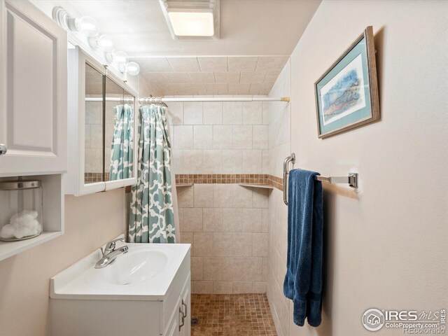 full bathroom featuring vanity and tiled shower